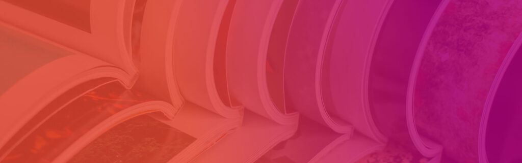 A close-up view of several open magazines or books stacked together, with pages fanned out. The image, produced by Sandy Alexander, features a warm pink and orange gradient overlay.