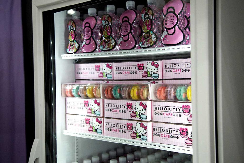 A refrigerator stocked by Sandy Alexander features Hello Kitty-themed bottles and boxes of colorful macarons, all with pink packaging and adorable Hello Kitty illustrations.